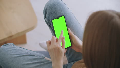 Woman-at-Home-Lying-on-a-Couch-using-Smartphone-with-Green-Mock-up-Screen-Doing-Swiping-Scrolling-Gestures.-Guy-Using-Mobile-Phone-Internet-Social-Networks-Browsing.-Point-of-View-Camera-Shot